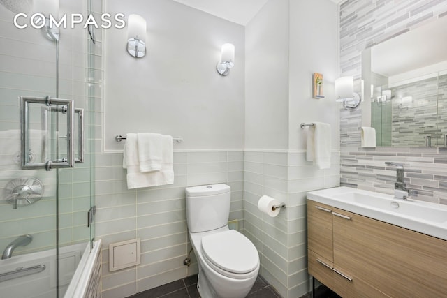 bathroom with toilet, vanity, tile walls, tiled shower / bath, and tile patterned floors