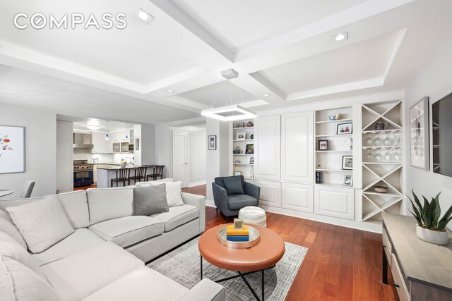 living area featuring beamed ceiling, coffered ceiling, wood finished floors, and recessed lighting