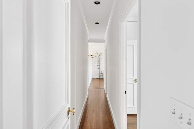 corridor with crown molding, baseboards, and wood finished floors