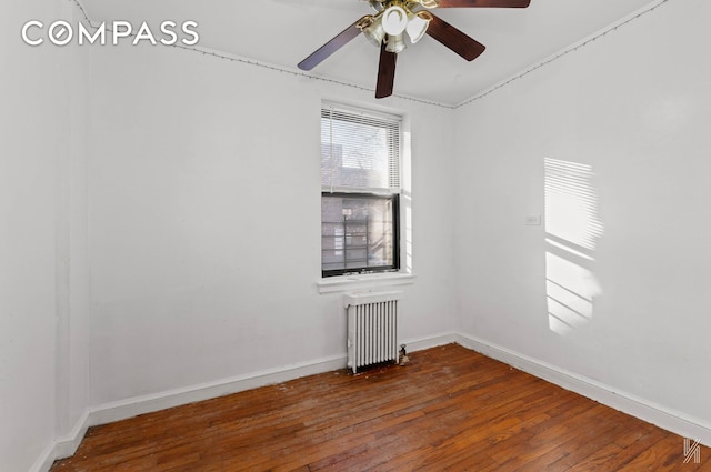 spare room with wood-type flooring, baseboards, radiator, and ceiling fan