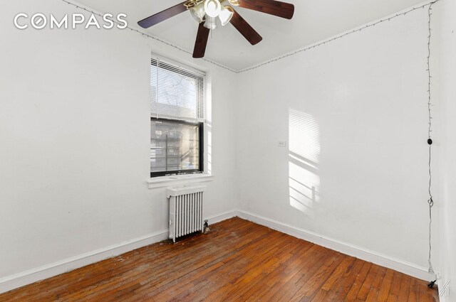empty room with radiator, baseboards, a ceiling fan, and hardwood / wood-style flooring