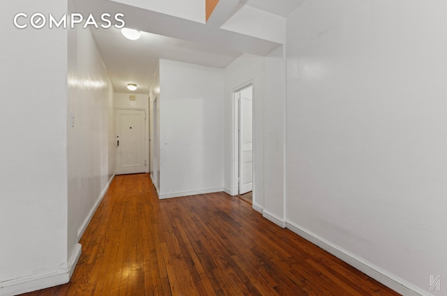 hall featuring wood-type flooring and baseboards