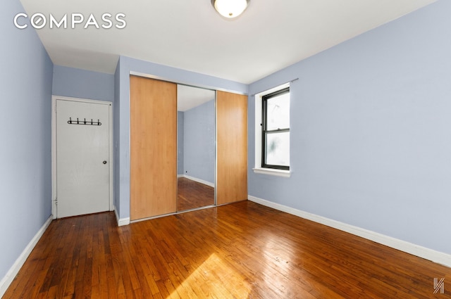 unfurnished bedroom with a closet, wood-type flooring, and baseboards