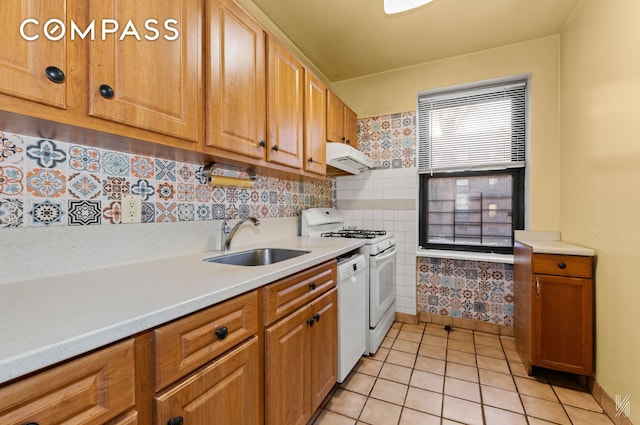kitchen with light tile patterned floors, white appliances, under cabinet range hood, light countertops, and a sink