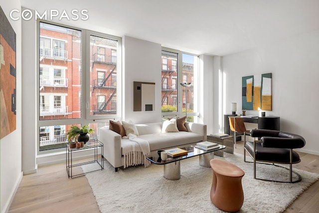 living room featuring a wealth of natural light, baseboards, light wood-style floors, and expansive windows