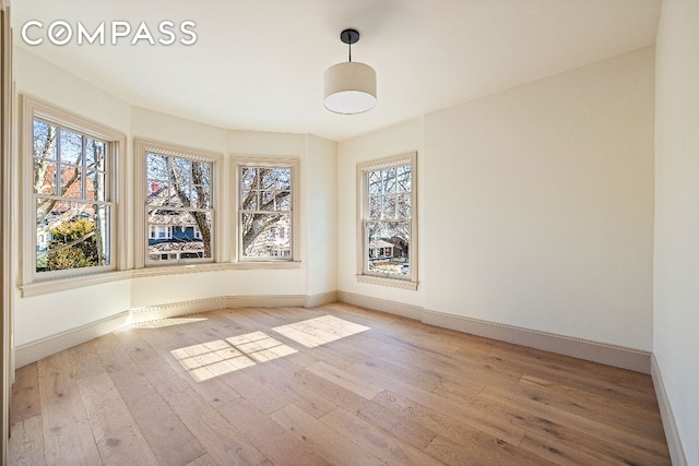 spare room with baseboards and wood finished floors