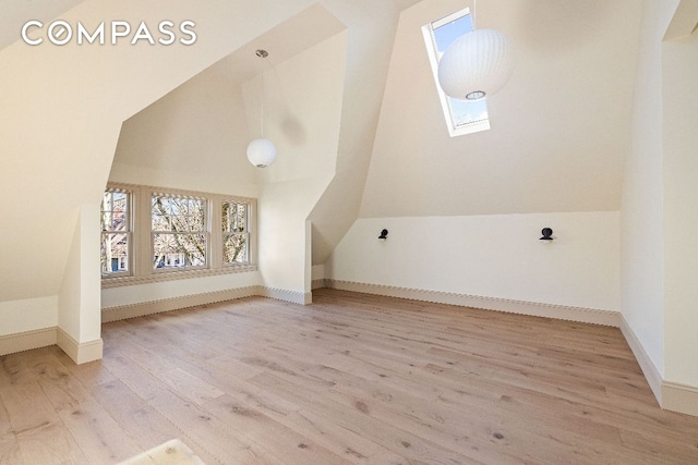 additional living space featuring lofted ceiling with skylight, baseboards, and wood finished floors