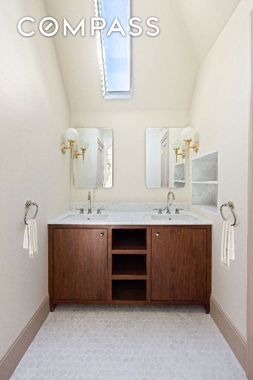 bathroom featuring lofted ceiling, a sink, and double vanity