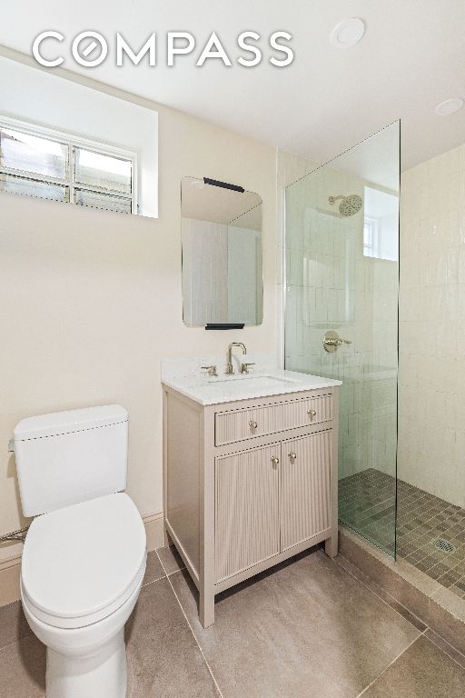 full bathroom with vanity, walk in shower, tile patterned flooring, and toilet