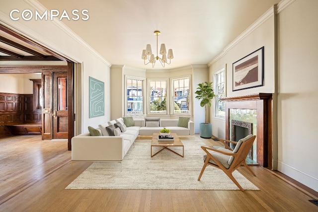 living area featuring ornamental molding, a high end fireplace, light wood finished floors, and an inviting chandelier