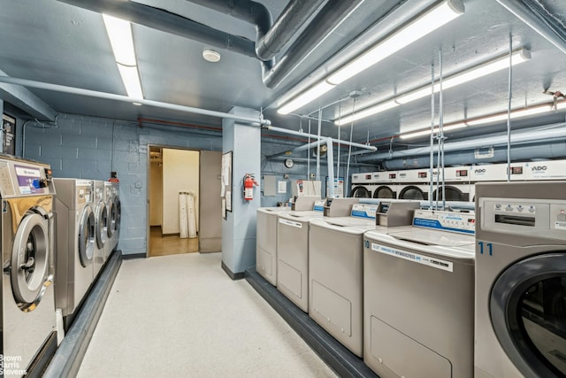 shared laundry area with light floors, concrete block wall, and washer and dryer