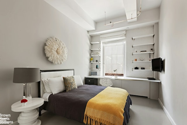 bedroom with finished concrete flooring and baseboards