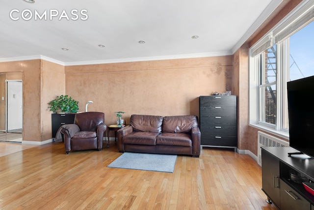 living area featuring baseboards, light wood-style floors, ornamental molding, and radiator heating unit