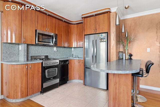 kitchen with brown cabinets, tasteful backsplash, appliances with stainless steel finishes, a breakfast bar area, and a peninsula