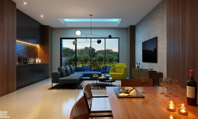 living room with a tray ceiling, speckled floor, and a skylight