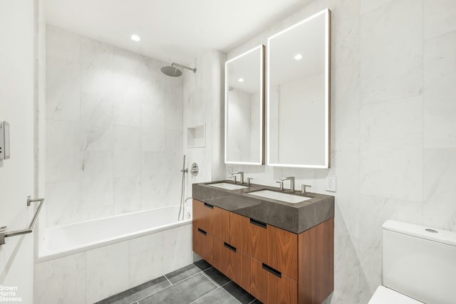 full bath featuring a sink, tiled shower / bath, toilet, and double vanity