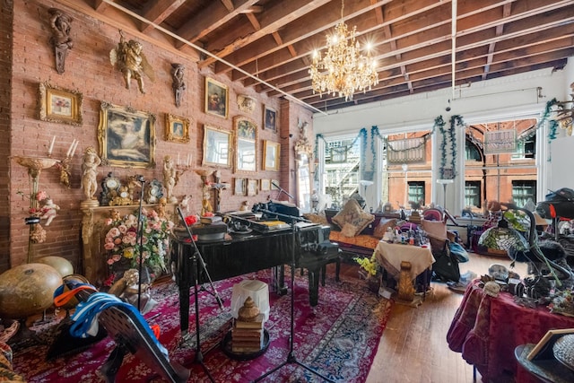 misc room featuring brick wall, an inviting chandelier, and wood finished floors