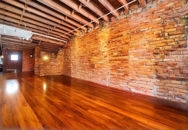 empty room with brick wall and wood finished floors