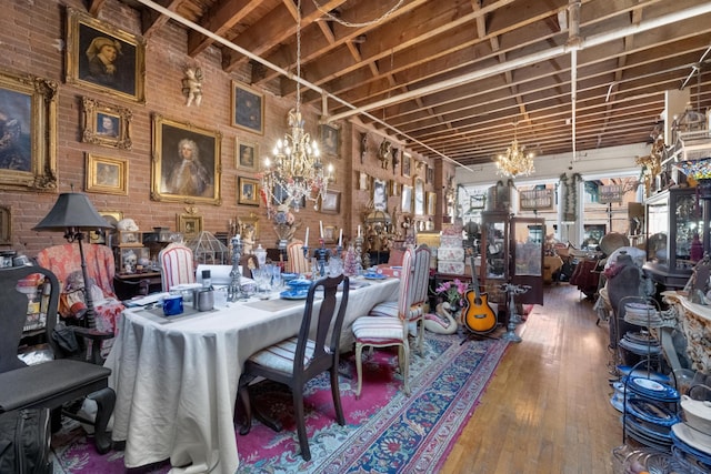 dining area with hardwood / wood-style flooring, a notable chandelier, and brick wall