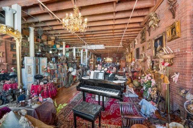 miscellaneous room featuring brick wall, an inviting chandelier, and wood finished floors