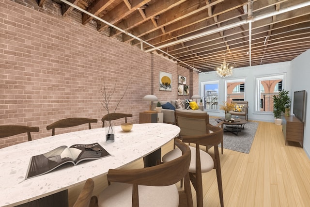 dining area with an inviting chandelier, brick wall, and wood finished floors