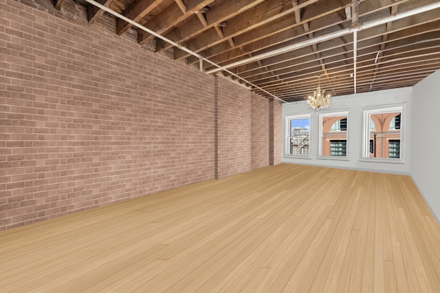 interior space featuring brick wall, wood finished floors, and an inviting chandelier