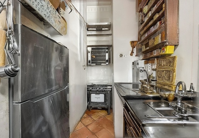 kitchen with a sink, freestanding refrigerator, and tile patterned floors