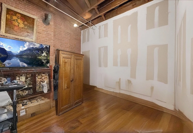 interior space with a towering ceiling, brick wall, and wood finished floors