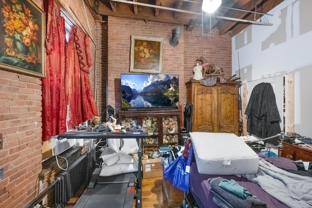 miscellaneous room featuring brick wall, a high ceiling, and wood finished floors