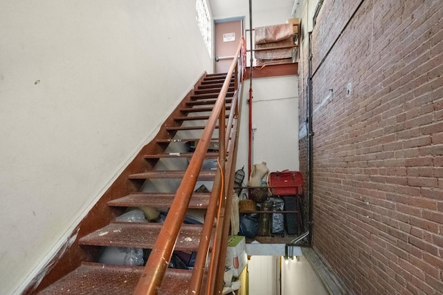 stairway featuring brick wall