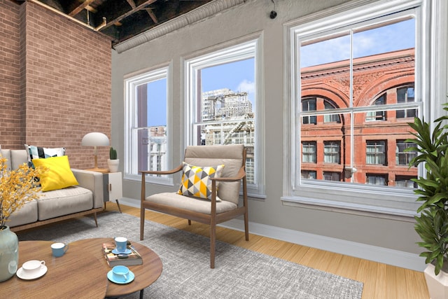 interior space featuring baseboards, a city view, brick wall, and wood finished floors