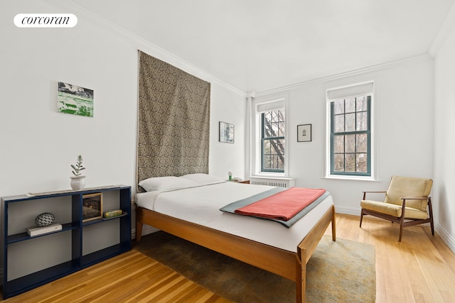 bedroom featuring baseboards, visible vents, crown molding, and light wood finished floors