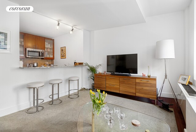 living area with indoor wet bar, rail lighting, visible vents, and baseboards