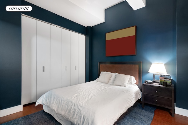 bedroom with a closet, dark wood finished floors, and baseboards