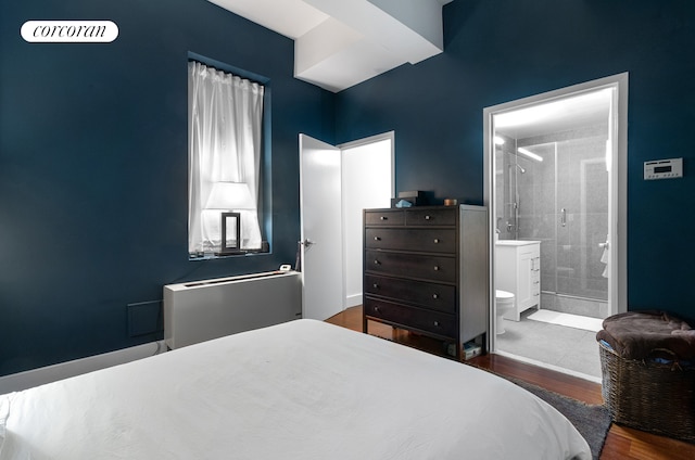 bedroom featuring ensuite bath and wood finished floors