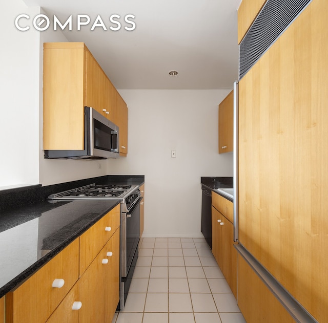 kitchen with light tile patterned floors, appliances with stainless steel finishes, and dark stone counters