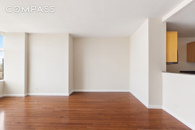 unfurnished room with baseboards and hardwood / wood-style floors