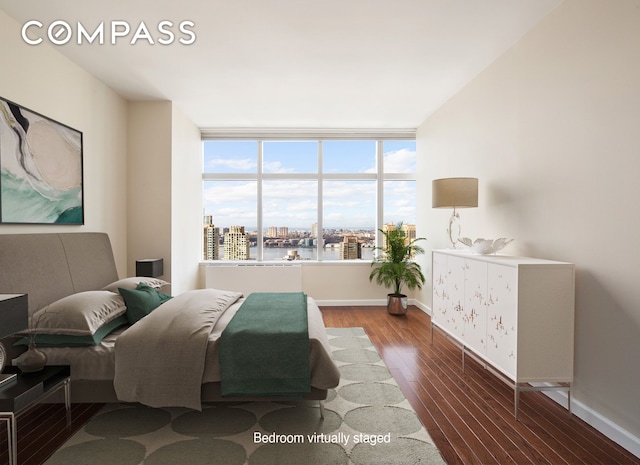 bedroom featuring baseboards, wood finished floors, and a city view