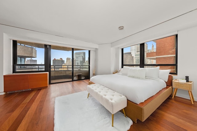 bedroom featuring access to exterior, wood finished floors, and a city view