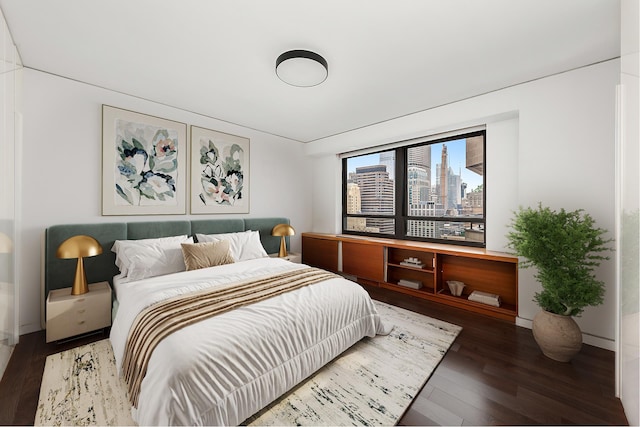 bedroom featuring wood finished floors, baseboards, and a city view