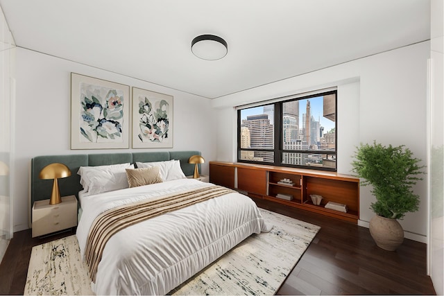 bedroom with a view of city, baseboards, and wood finished floors