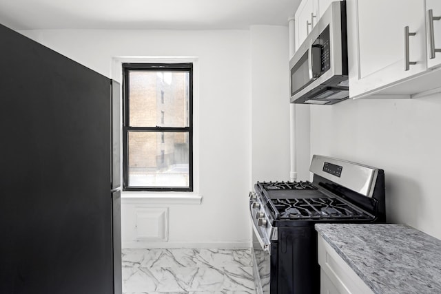 kitchen featuring white cabinets, marble finish floor, stainless steel appliances, and light stone countertops