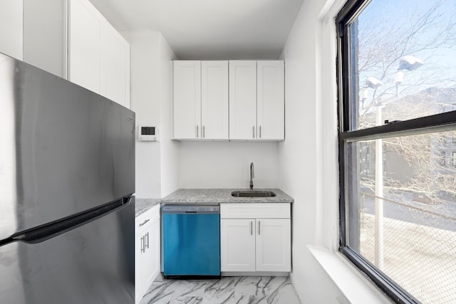 kitchen featuring marble finish floor, a wealth of natural light, freestanding refrigerator, a sink, and dishwashing machine