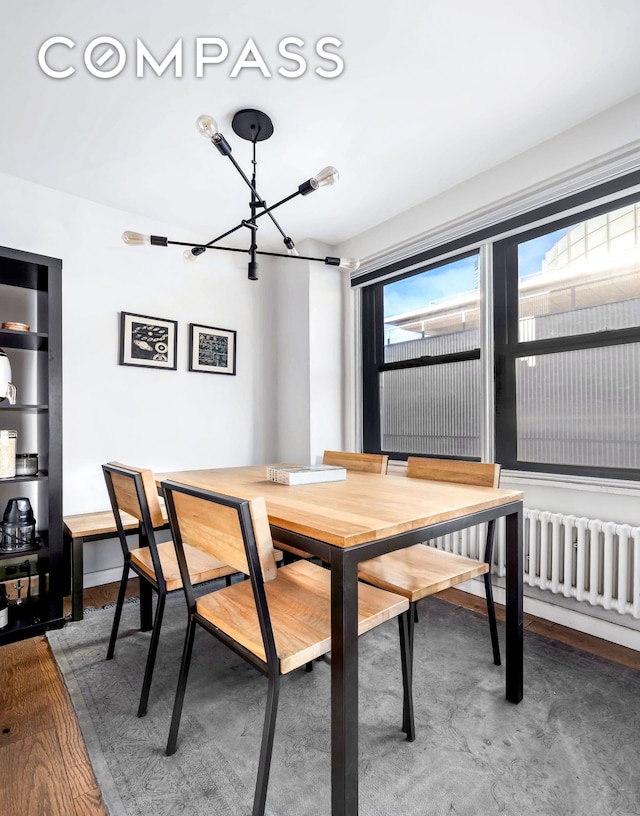 dining space with a chandelier, radiator heating unit, baseboards, and wood finished floors