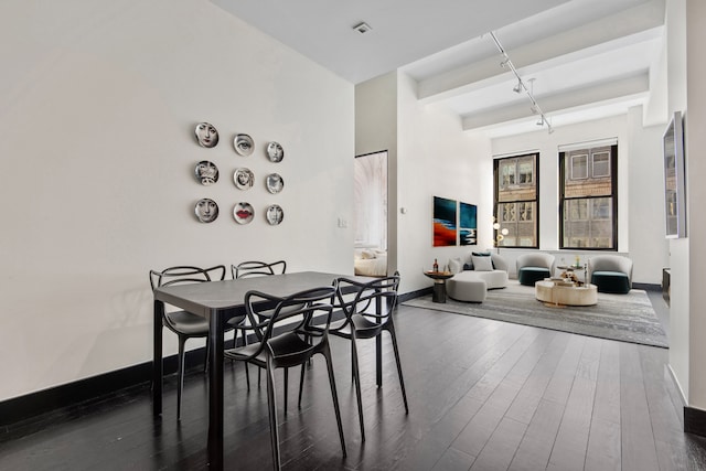 dining area with baseboards, dark wood finished floors, and beamed ceiling