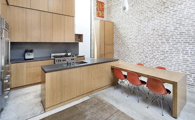 75 Warren St, New York City, NY 11201 - kitchen with dark countertops, a kitchen island with sink, a sink, modern cabinets, and concrete flooring