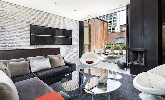 living area featuring brick wall, a healthy amount of sunlight, and floor to ceiling windows