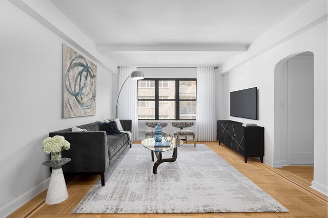 living area with arched walkways, beamed ceiling, and baseboards