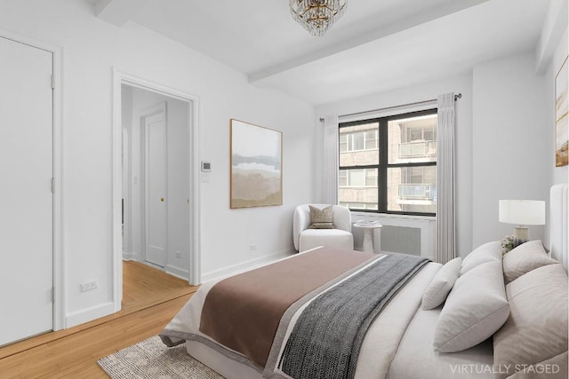 bedroom with light wood finished floors, beamed ceiling, and baseboards