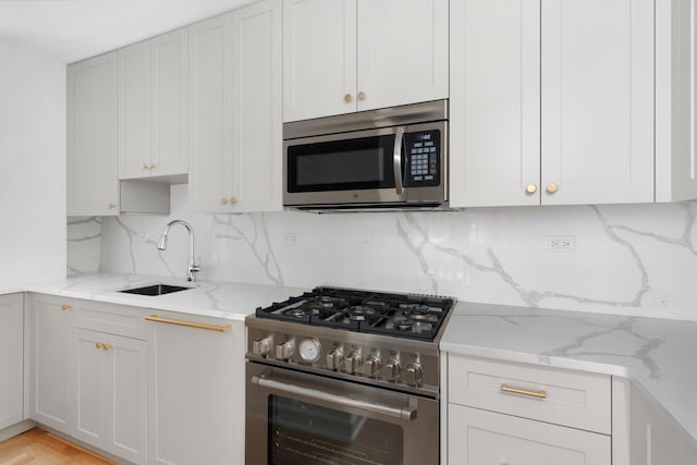 225 E 79th St Unit 7Cd, New York City, NY 10075 - kitchen featuring stainless steel appliances, a sink, decorative backsplash, light stone counters, and white cabinetry